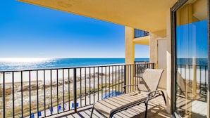 A balcony with a view of the beach and ocean.