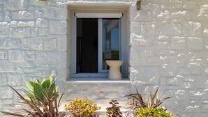 Un bâtiment en pierre avec une fenêtre et un objet blanc fixé au mur.