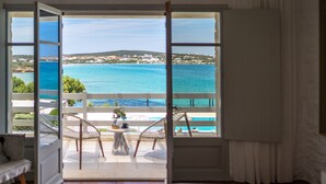 Un balcon ouvert donnant sur la mer et sur une ville située au loin.