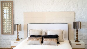 Un lit bien fait, avec une tête de lit, deux tables de chevet avec des lampes et un mur à texture.