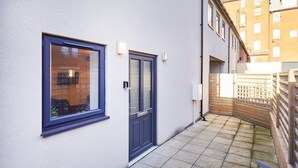 A narrow alleyway with a white building, a dark blue door, and a window with a metal frame. - Host & Stay | West Cliff Retreat (Whitby)
