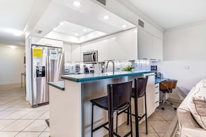 Una cocina moderna con una isla central, electrodomésticos de acero inoxidable y una zona de asientos con taburetes de bar.