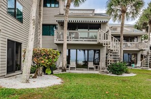 A multi-story building with balconies, a covered patio, and palm trees.