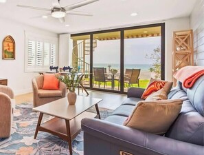 A living room with a sofa, chairs, a coffee table, and a view of the ocean. - Sonrisa 5 2BR Gulf-Front Condo (Belleair Beach)