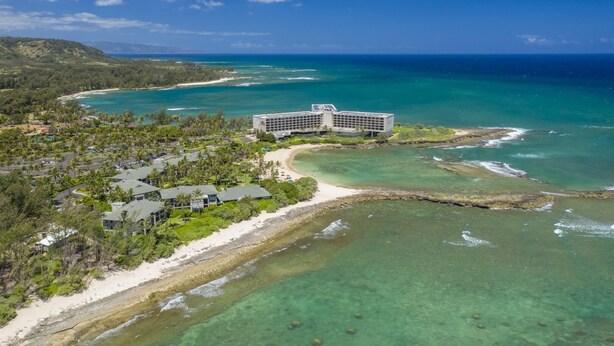 Une station balnéaire dotée d’un grand bâtiment, de propriétés situées en bord de mer et d’eaux d’un bleu limpide.