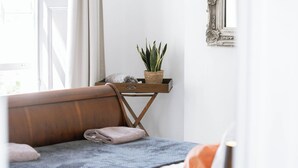 Een gezellige kamer met een houten bankje, een klein tafeltje met een plant en een witte muur met decoratief lijstwerk.
