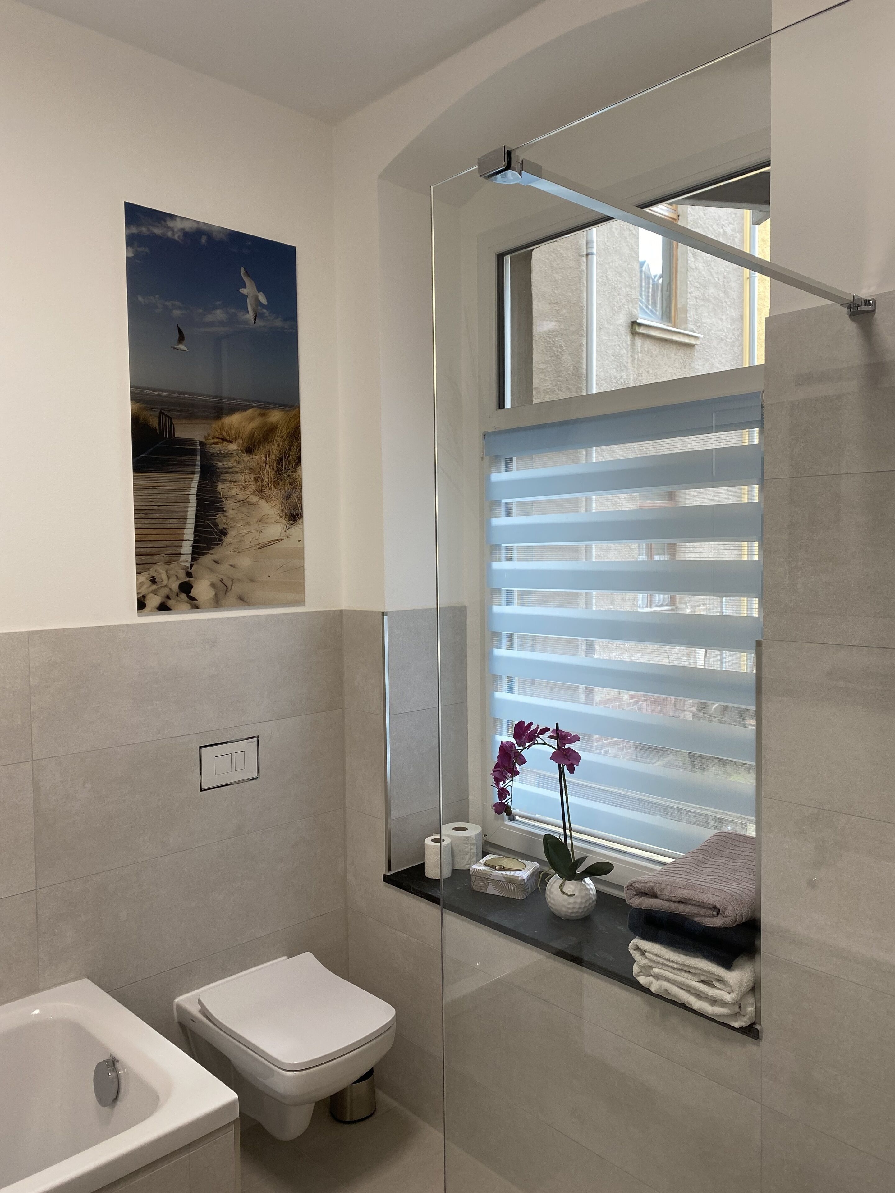 Un baño moderno con cabina de ducha de vidrio, inodoro, bidé y repisa con artículos de aseo.