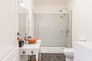 Un baño moderno con un lavabo blanco, cabina de ducha de vidrio y un inodoro blanco.