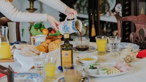 A breakfast table with various food items, drinks, and a jug of coffee being poured. - Casa do Salgueiral (Santa Marta de Penaguião)