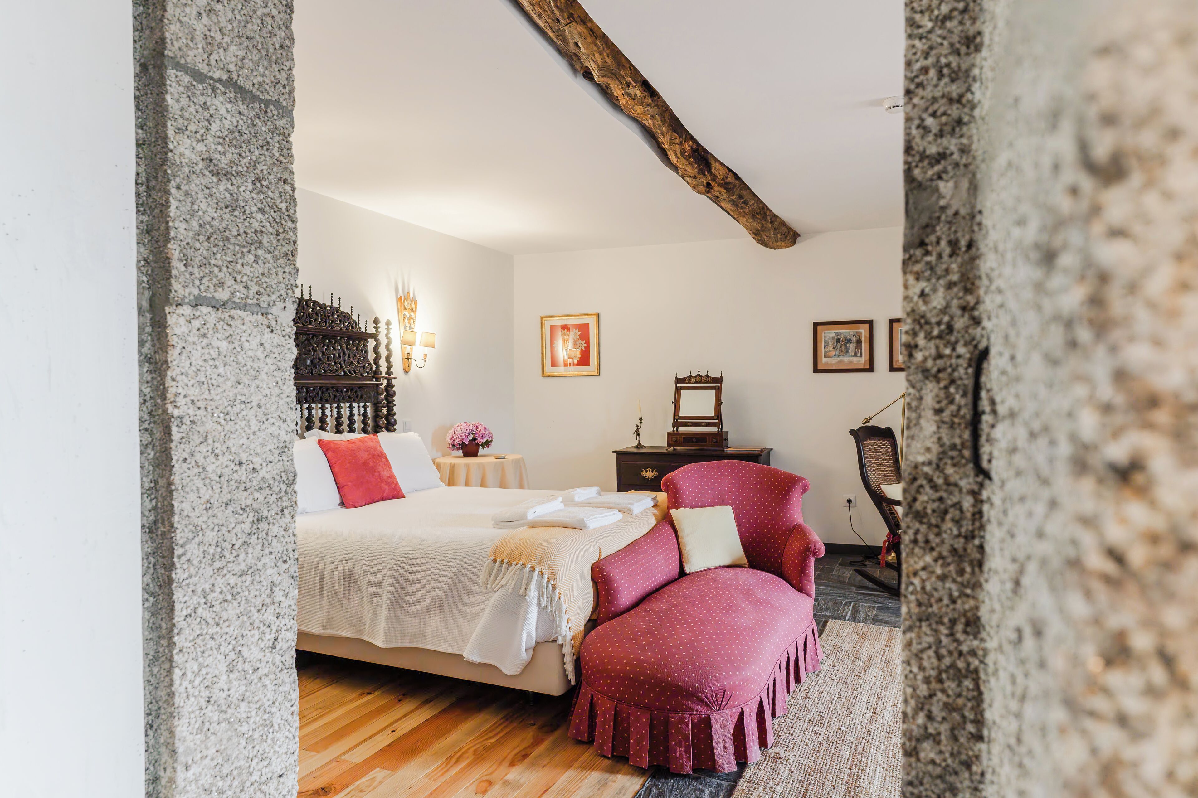 A bedroom with a bed, a chair, a nightstand, and a wall-mounted shelf.