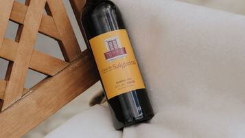 A bottle of wine on a white cloth next to a wooden chair.