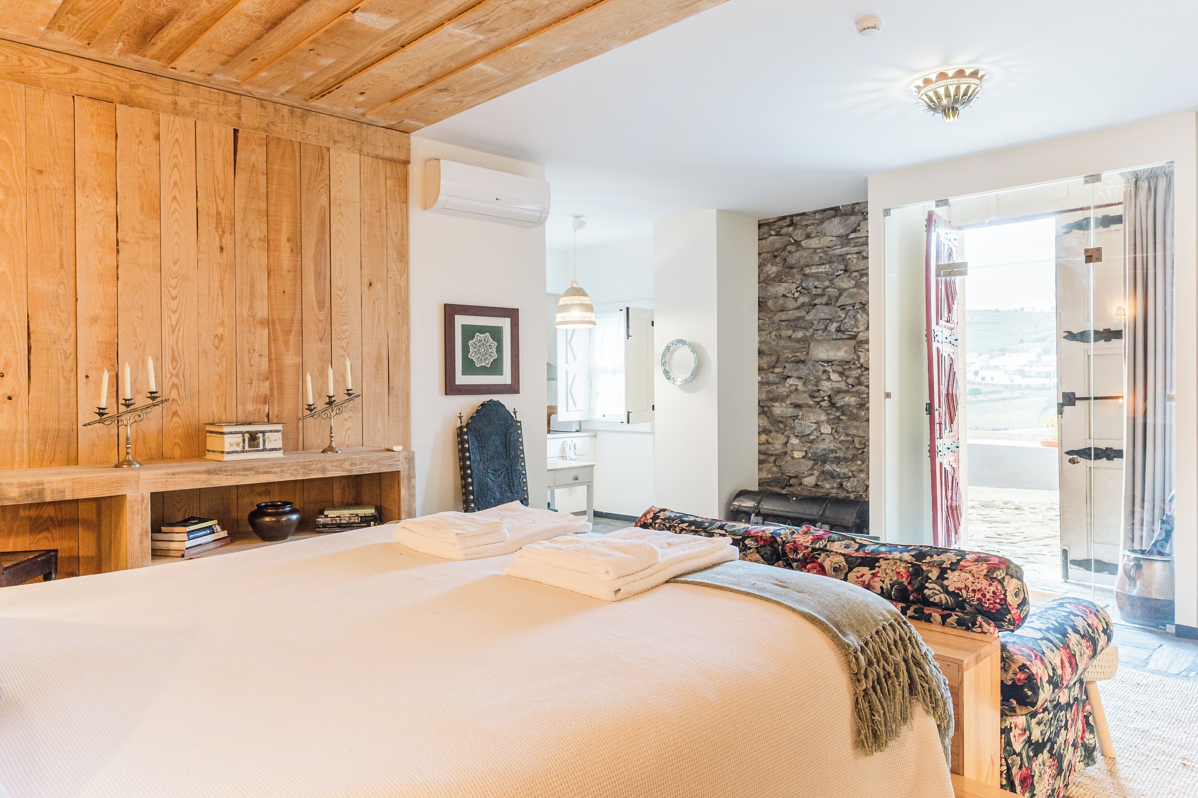 Un dormitorio con una cama grande, armario de madera y pared de piedra.