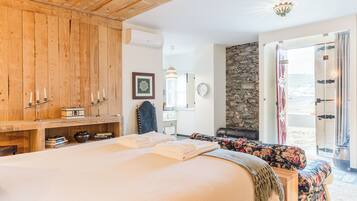 Un dormitorio con una cama grande, armario de madera y pared de piedra.