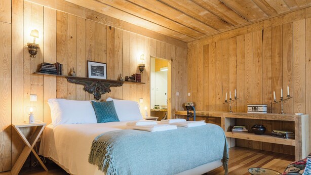A wooden-paneled room with a bed, bedside tables, a mirror, and a shelf with books and candles. - Casa do Salgueiral (Santa Marta de Penaguião)