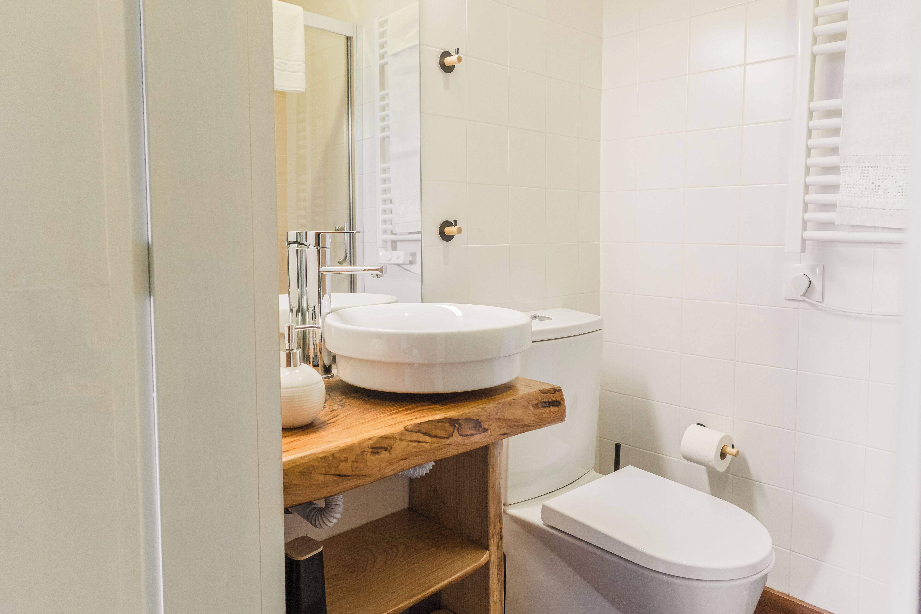 Ein Badezimmer mit einem Holzkonsolenunterschrank, einem weißen Waschbecken, einer Toilette und einem Handtuchhalter.