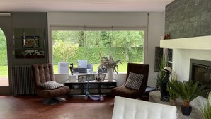 Un salón amplio con chimenea, ventanas grandes y asientos cómodos.