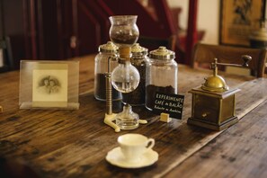 A wooden table with coffee-making equipment, a cup, and a sign reading "EXPERIMENTATE CAFÉ de BALÃO."