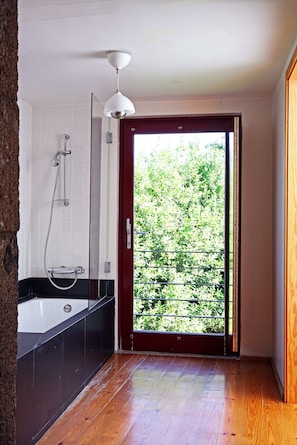 Een moderne badkamer met een douchecabine van glas, een wit plafond en een houten vloer.