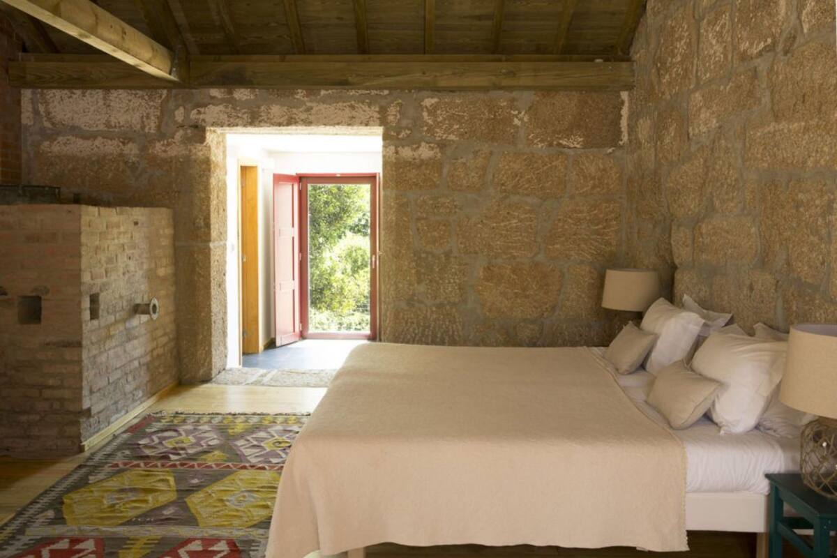 Ein Schlafzimmer mit einem Bett, Kissen, einem Nachttisch mit Lampe und einem gemusterten Teppich.
