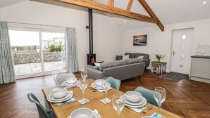 Un coin repas avec une table en bois dressée pour six personnes, un canapé et une cheminée.