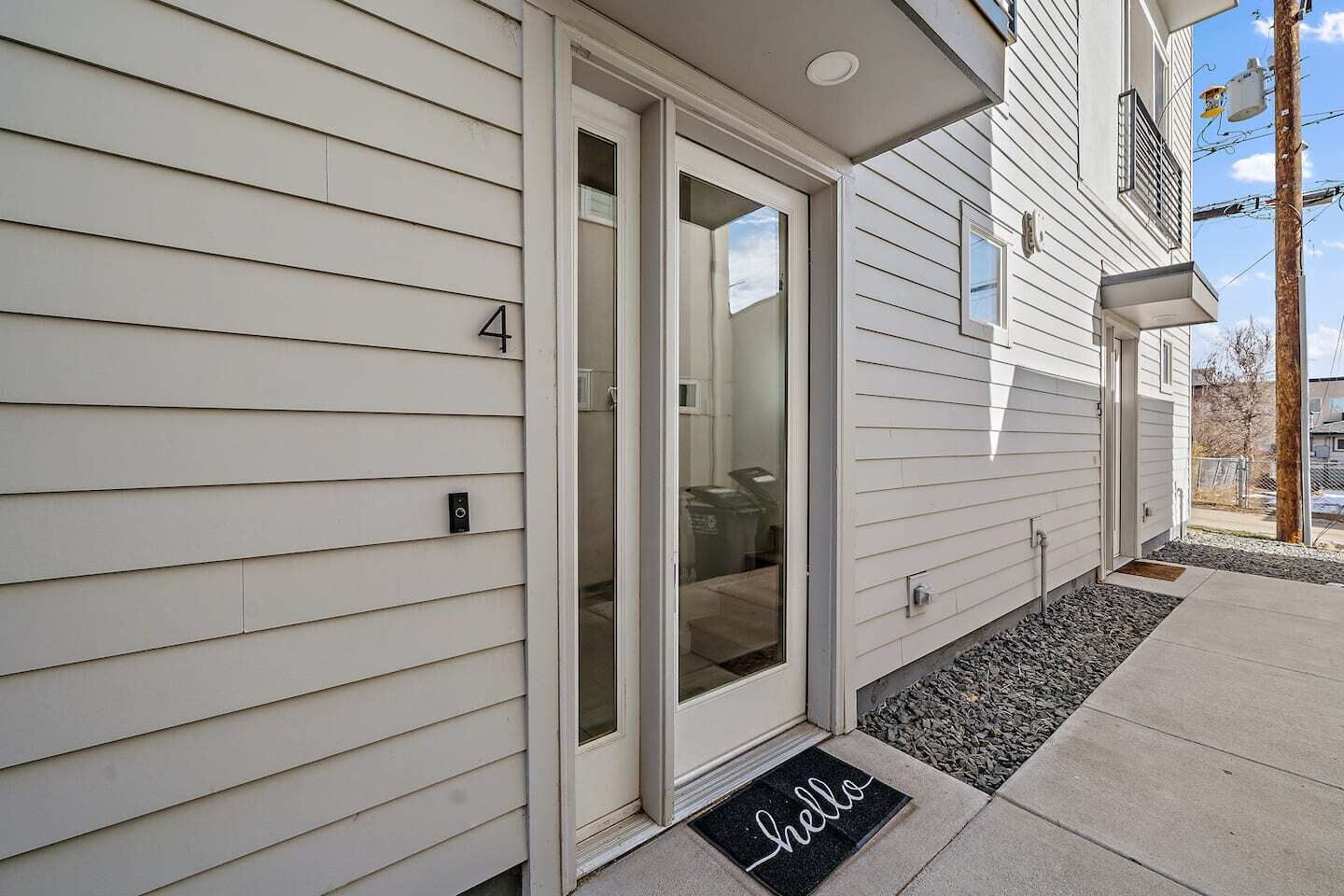 A residential building with a sliding glass door entrance, a mailbox, and a doormat with the word "hello".