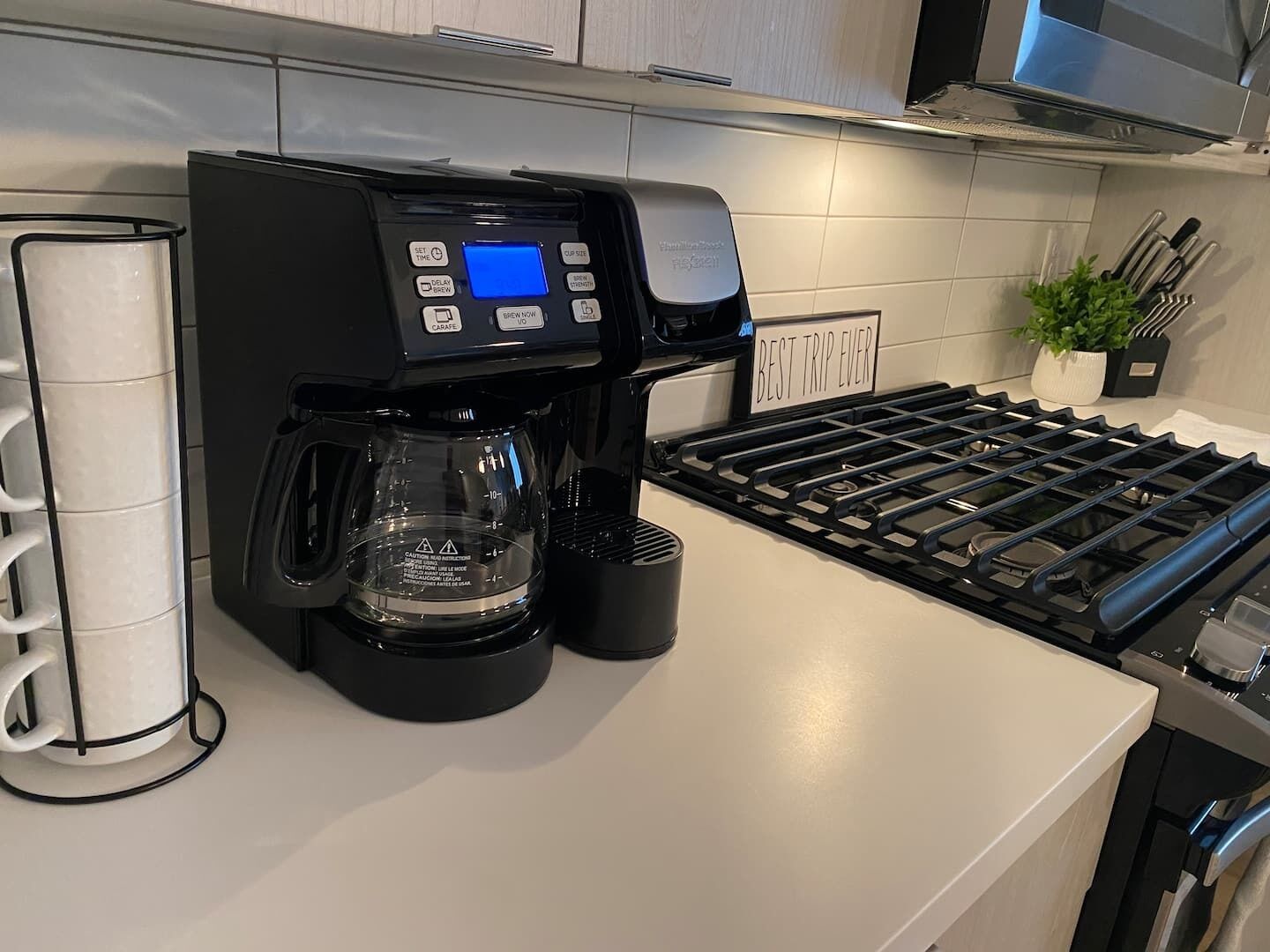 A modern kitchen with a coffee maker, a kettle, and a stove.