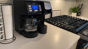 Una cocina moderna con cafetera, hervidor y estufa.