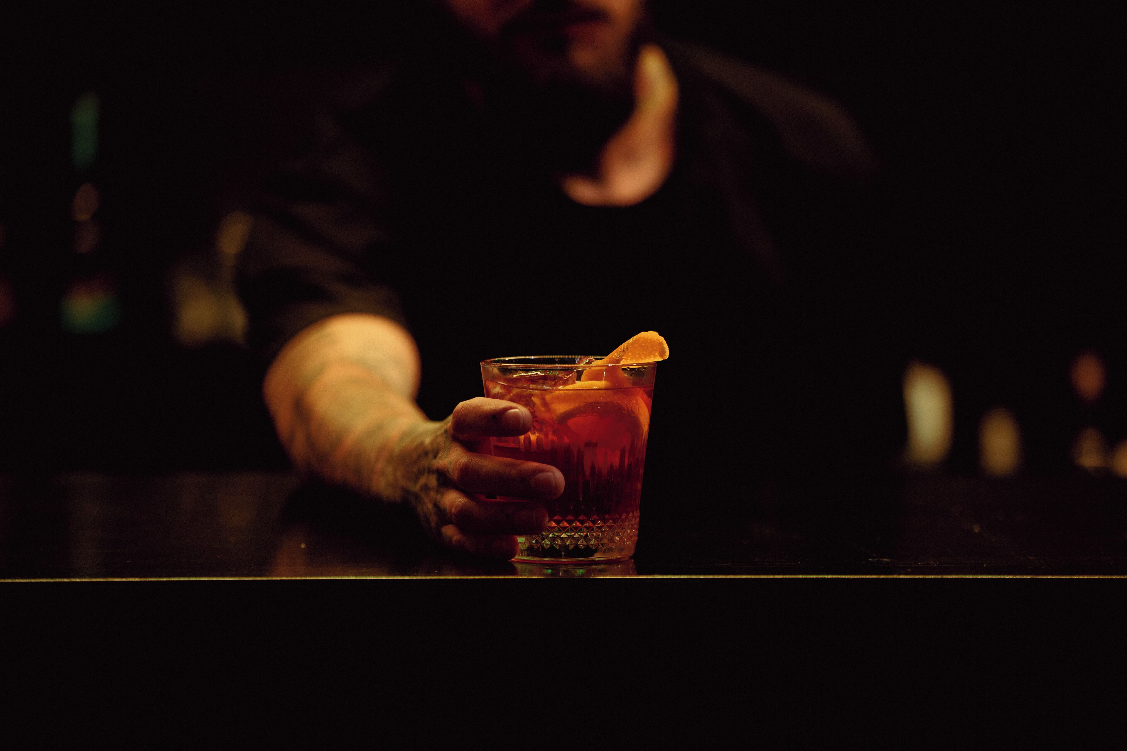 A person holding a glass with a lemon slice.