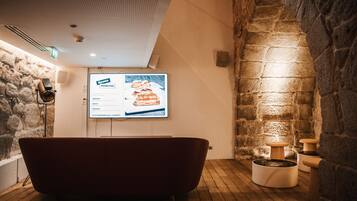 A modern bathroom with a stone wall, a red bathtub, and a wooden floor.