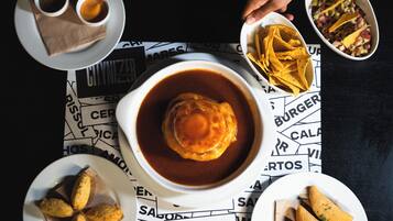 A table with various dishes including a bowl of soup, a plate of chips, and a bowl of salsa.