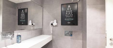 Un baño moderno con azulejos grises, un lavamanos blanco, un espejo y un inodoro.