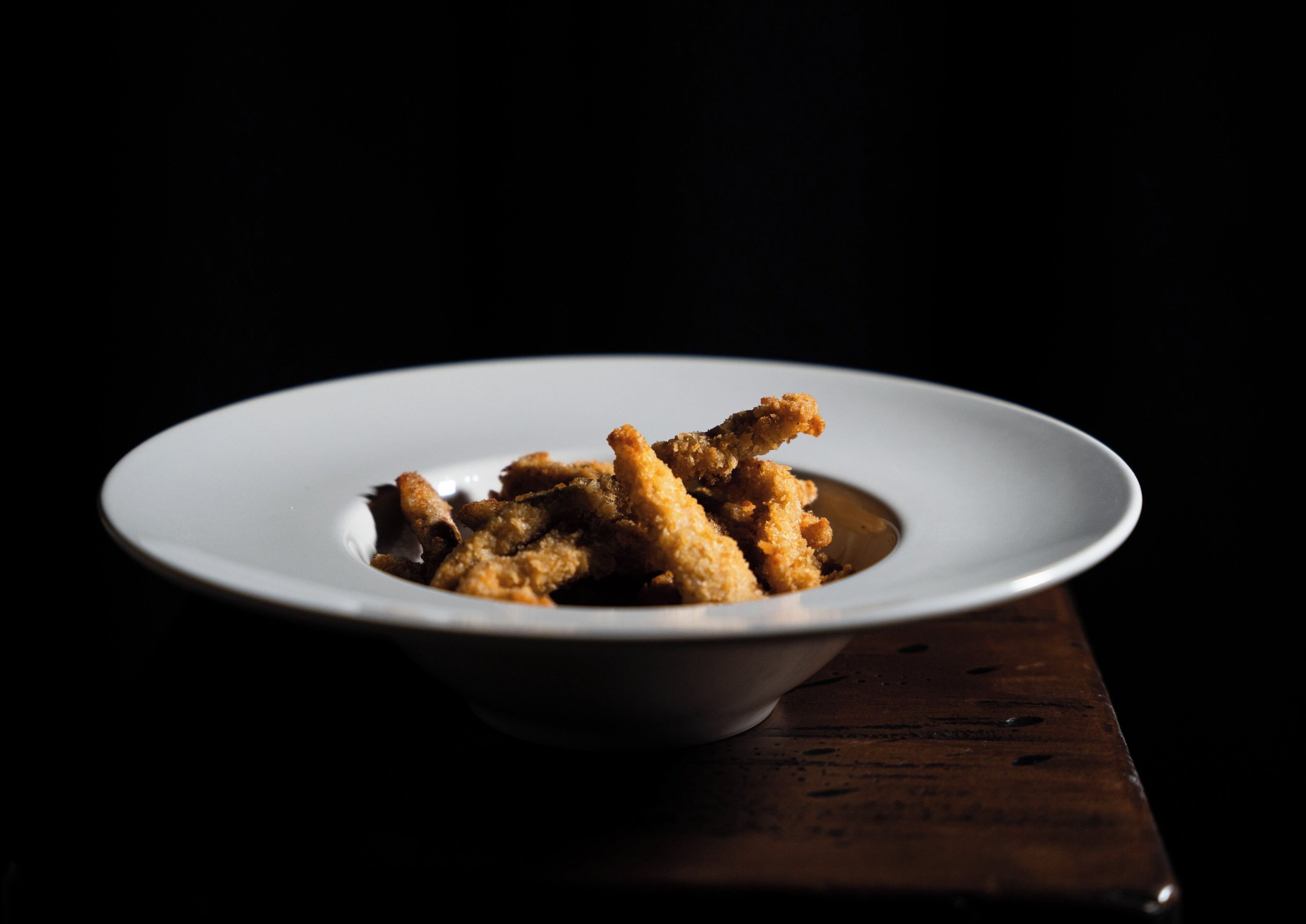 A white plate with fried food on a dark background.