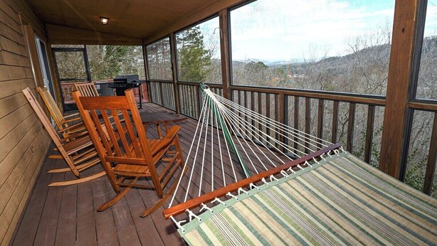 A wooden deck with a hammock, rocking chairs, and a grill area. - Close to Town • Mountain Views • Fast Wifi • Pet Friendly (Murphy)
