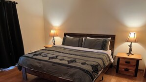 A bed with a patterned blanket, two bedside lamps, and a wooden nightstand with a drawer. - Close to Town • Mountain Views • Fast Wifi • Pet Friendly (Murphy)