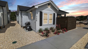 Une maison de plain-pied avec un petit jardin à l’avant, une allée en gravier et une clôture en bois.