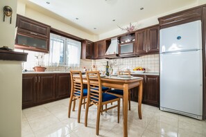 Una cocina con armarios de madera, un refrigerador blanco y una mesa de comedor con sillas.