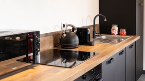 Una cocina moderna con encimera de madera, un hervidor, una cafetera y un lavabo.