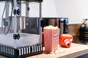 Eine Popcornmaschine, ein rot-weiß gestreifter Popcorntopf und ein Holztisch.