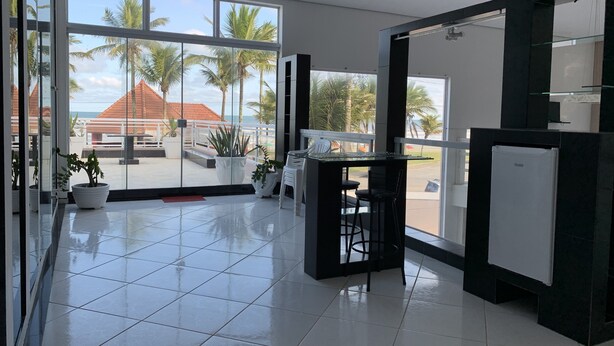 A modern kitchen with large windows, a bar area, and potted plants. - Beachfront House (SP)