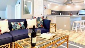 A modern living room with a sofa, a glass coffee table, and a wine bottle. - Channel View Residence at the Dygert House (Clayton)