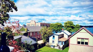 A residential neighborhood with houses, a lawn, and a body of water in the background. - Channel View Residence at the Dygert House (Clayton)