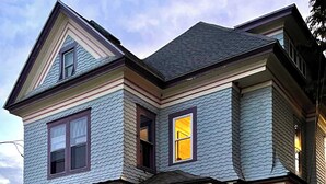 A two-story house with a brick facade, a front porch with steps, and a small garden. - Channel View Residence at the Dygert House (Clayton)