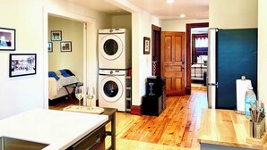 Un espacio habitable compacto con cocina, una mesa de comedor y zona de lavandería con lavadoras apiladas.