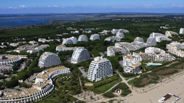 A residential area with modern, dome-shaped buildings clustered together, surrounded by greenery and a body of water in the background. - T.2 SUPERB SEA VIEW "COCOONING FAVORITE" CLASS 2 STARS!!!! (La Grande-Motte)