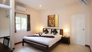 A bedroom with a bed, bedside tables, a wall-mounted air conditioner, a window with curtains, a door, and a ceiling fan. - K-Bunk Villa Ao Nang (Krabi)