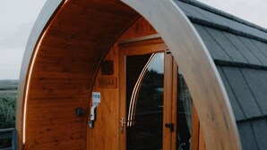 Una cabaña de madera acogedora, con techo curvo y puerta de cristal.