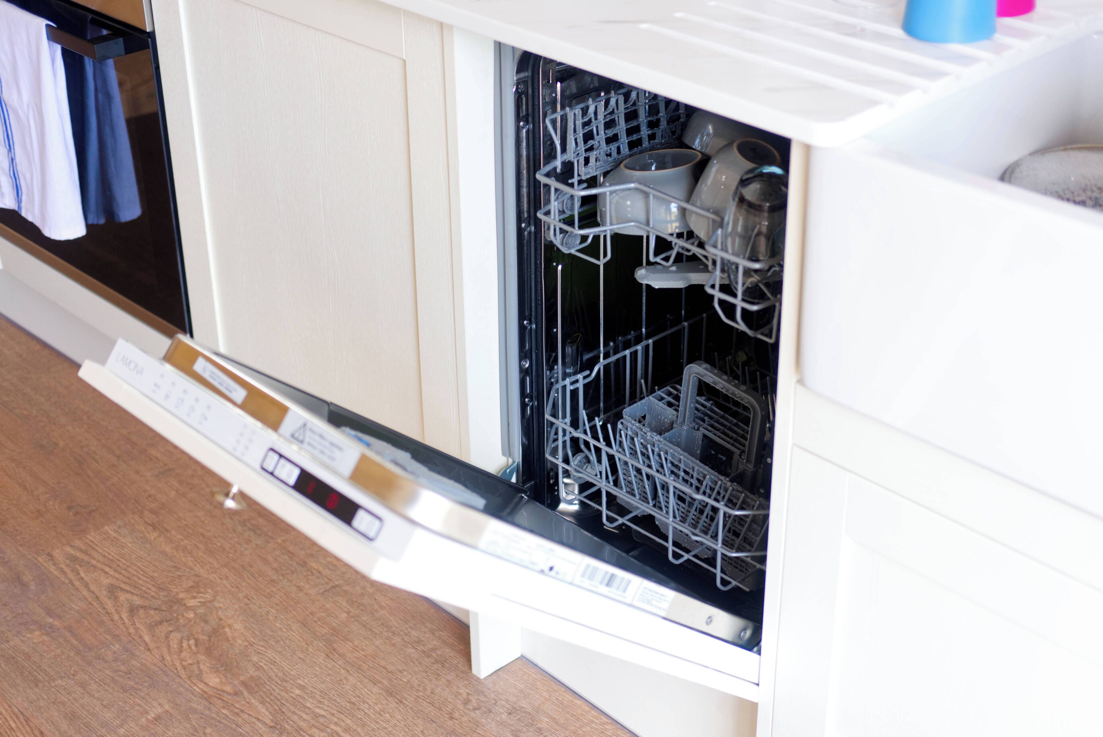 An open dishwasher with various dishes and utensils inside.