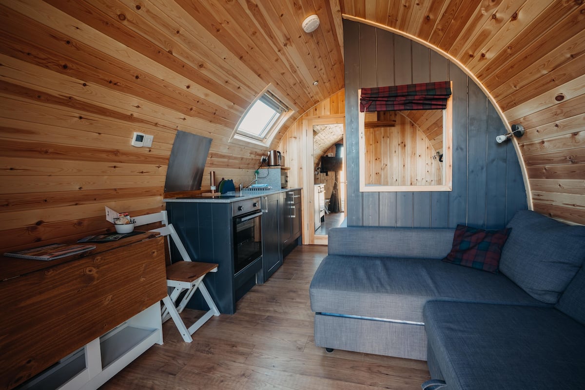 A compact, wooden interior with a kitchenette, a sofa, and a dining area.