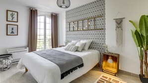 A bedroom with a large bed, a hanging light fixture, a patterned wall, and a potted plant. - Lion King Suite - 4P near Disneyland Paris (Montry)