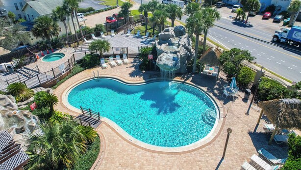 Una piscina con design a forma di cuore, circondata da palme e una cascata artificiale rocciosa.
